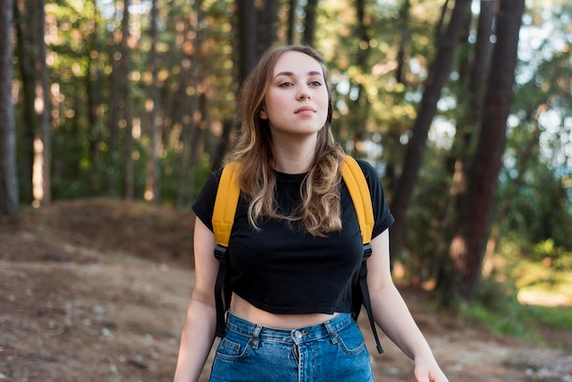 Mid shot blonde girl with backpack in woods