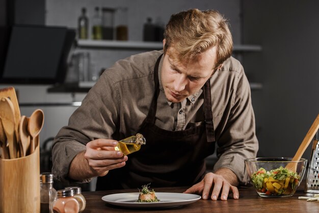 Mid shot chef plating dish with oil