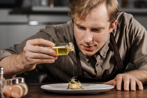 Mid shot chef plating dish with olive oil