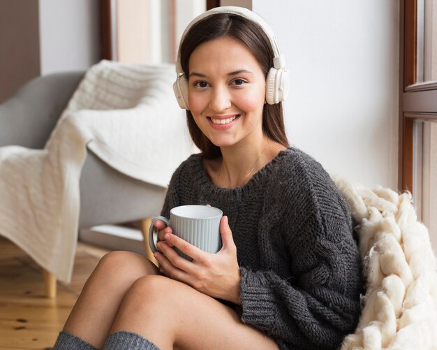 Mid shot cozy woman with blanket and mug