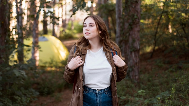 Mid shot girl with backpack in front of tent