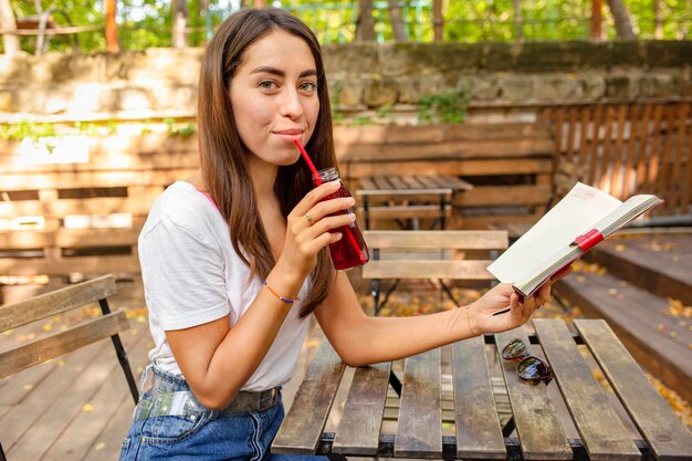 Девушка в середине кадра с книгой и бутылкой свежего сока