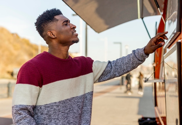 Mid shot male reading food truck menu