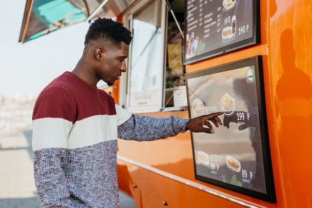 Mid shot man reading food truck menu