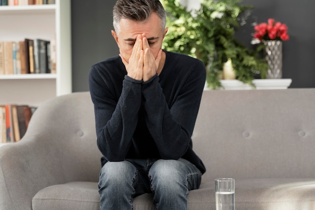 Mid shot man sitting on couch in therapy cabinet