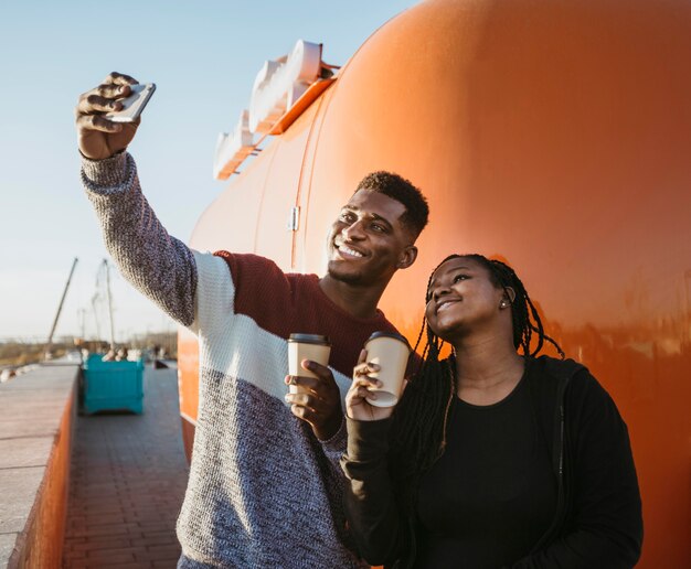 Mid shot man and woman taking selfie by food truck