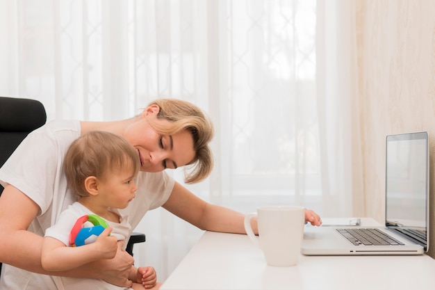 Mid shot mother and baby at desk