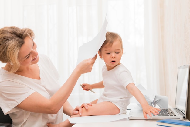 Mid shot mother hiding baby behind papers