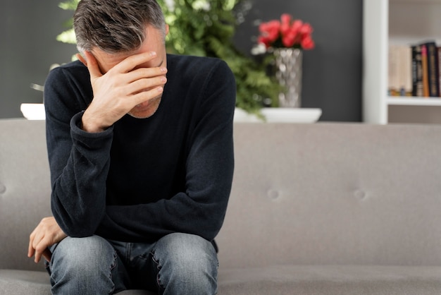 Mid shot patient sitting on couch in therapy cabinet