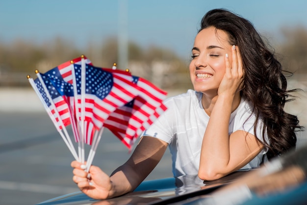 車にアメリカのフラグを保持している半ばショット笑顔の女性