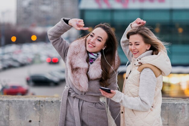 Mid shot smiling women with earphones on roof