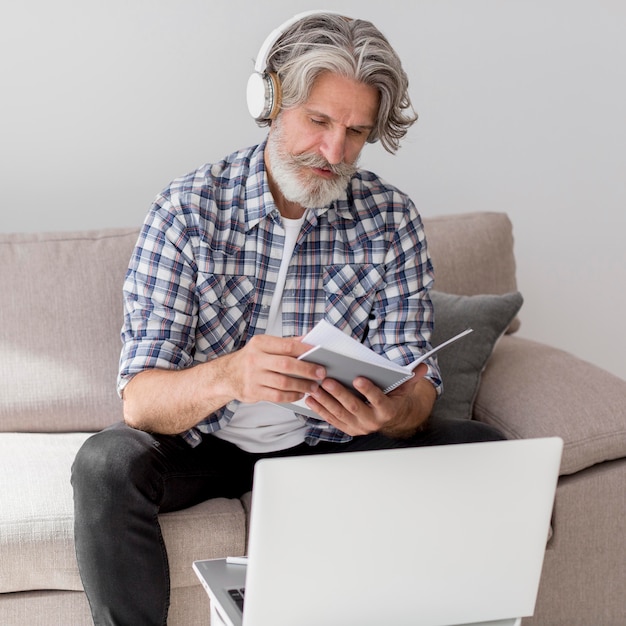 Free photo mid shot teacher looking at notebook near laptop