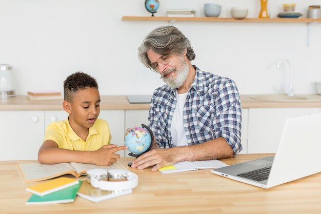 Mid shot teacher showing earth globe to student