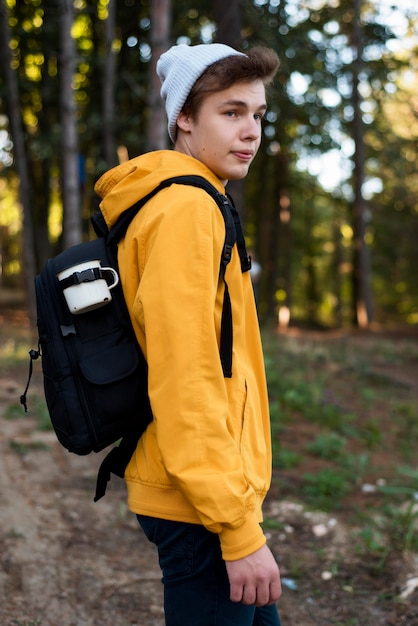 Free photo mid shot teen with backpack in forest