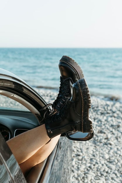 Mid shot woman feet out of car window near sea