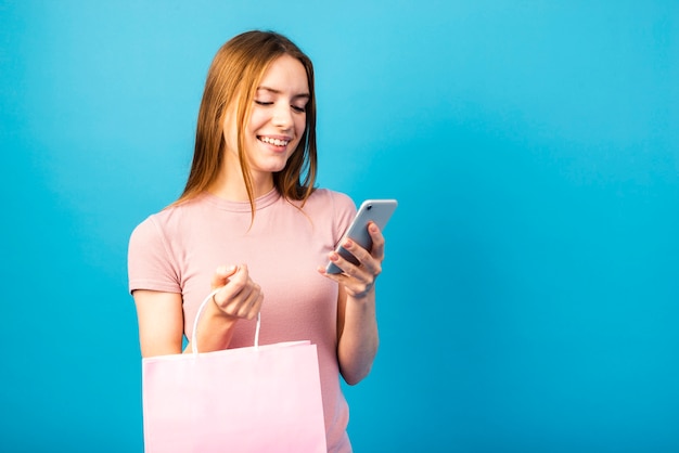 Free photo mid shot woman holding bag and looking at phone