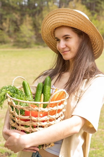 Mid shot woman holding basket with groceries looking away