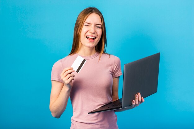 Mid shot woman holding credit card and laptop