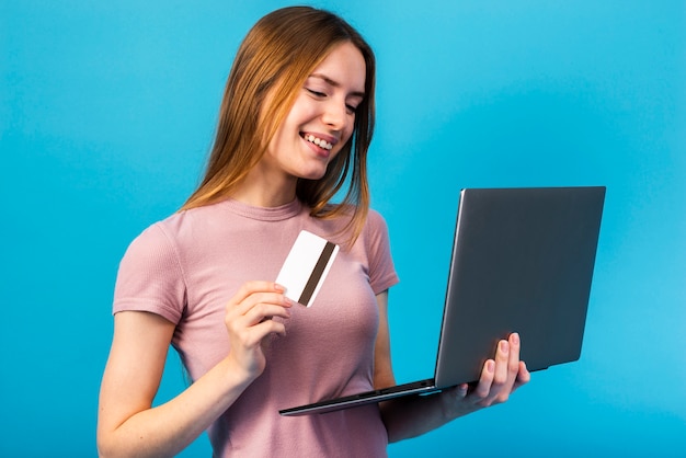 Mid shot woman holding credit card and looking at laptop