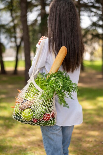 Mid shot woman holding reusable bag outside