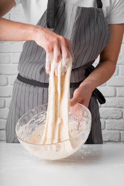 Mid shot woman kneading dough in bowl
