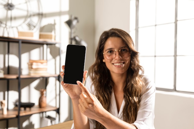 Mid shot woman showing phone