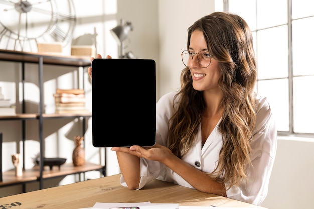 Mid shot woman showing tablet