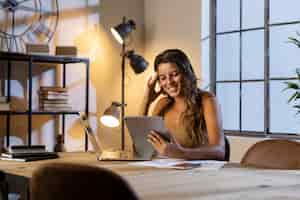 Free photo mid shot woman at table holding tablet