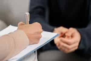 Free photo mid shot woman therapist taking notes in clipboard