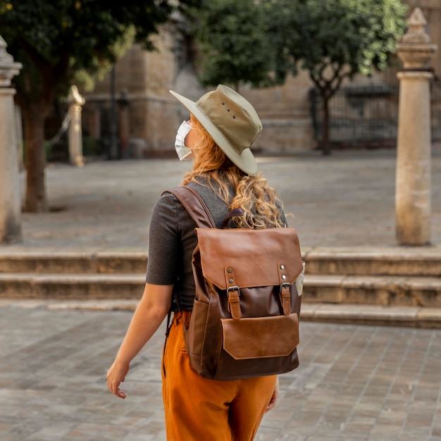 mid shot woman walking through city wearing mask