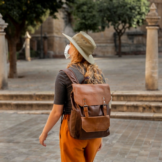 Foto gratuita donna a metà colpo che cammina attraverso la città che indossa la maschera