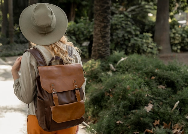 Donna a metà colpo con cappello a piedi nella natura