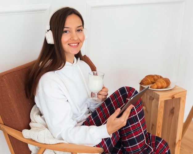 Free photo mid shot woman with tablet in armchair