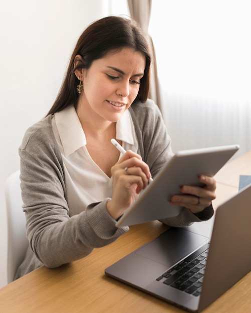 Mid shot woman working at home on tablet