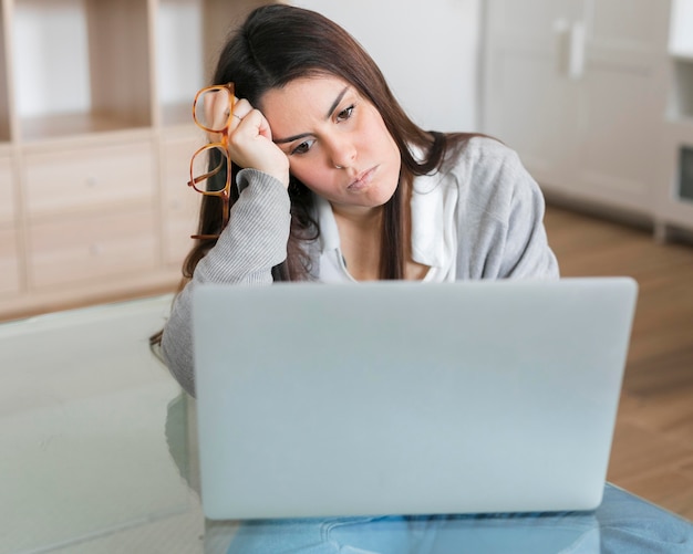 Mid shot woman working on laptop and holding glasses