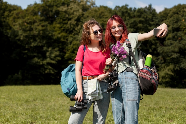 Donne a metà tiro che prendono selfie in natura