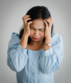 Middle age asian woman feeling pain and suffer from sudden headache and brain stroke attack and hold her head with suffer face. concept of brain and head problem.
