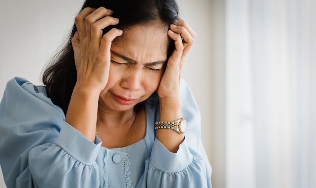 Middle age asian woman feeling pain and suffer from sudden headache and brain stroke attack and hold her head with suffer face. concept of brain and head problem.