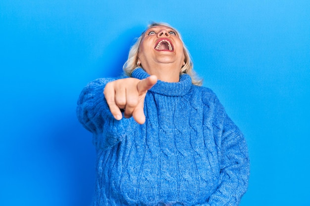 Free photo middle age blonde woman wearing casual clothes laughing at you, pointing finger to the camera with hand over body, shame expression