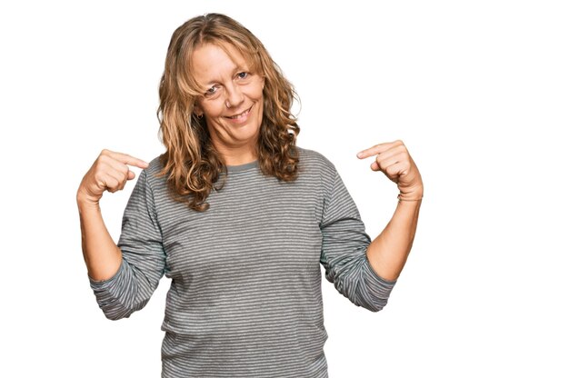 Middle age blonde woman wearing casual clothes looking confident with smile on face pointing oneself with fingers proud and happy