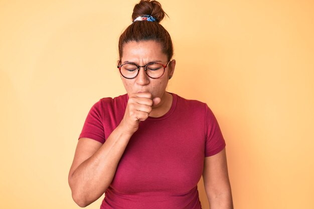 Middle age brunette hispanic woman wearing casual clothes and glasses feeling unwell and coughing as symptom for cold or bronchitis health care concept