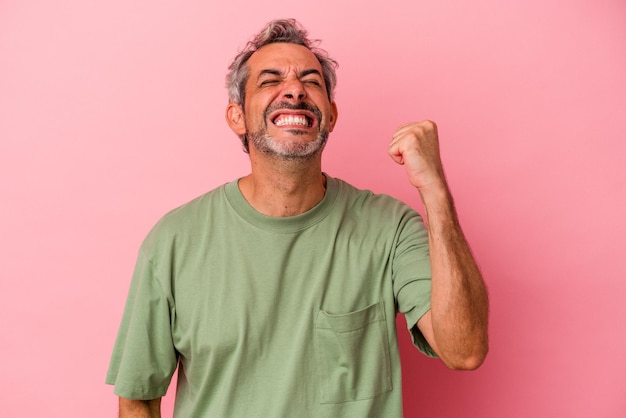 Middle age caucasian man isolated on pink background  celebrating a victory, passion and enthusiasm, happy expression.