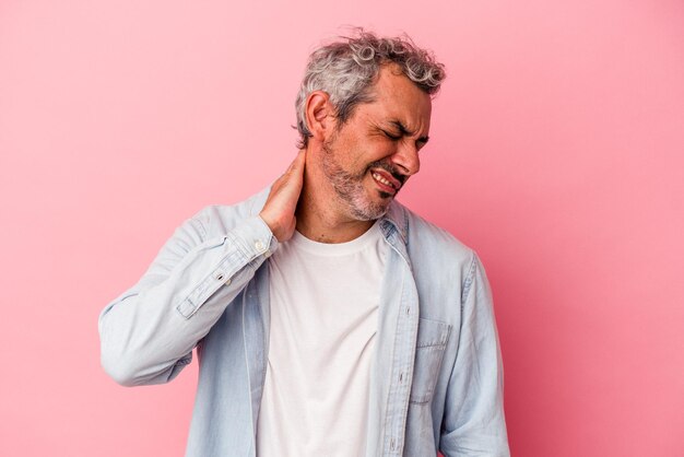 Middle age caucasian man isolated on pink background  having a neck pain due to stress, massaging and touching it with hand.