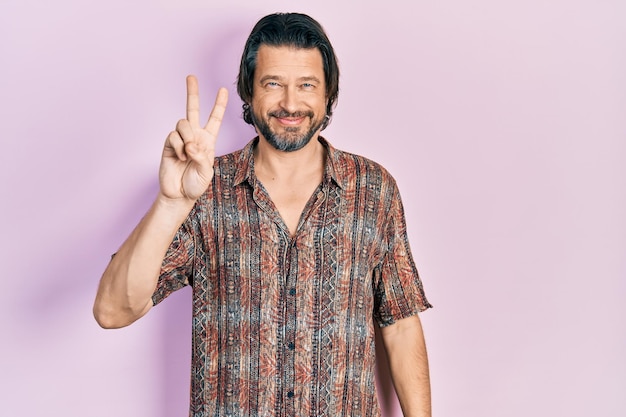 Middle age caucasian man wearing casual clothes showing and pointing up with fingers number two while smiling confident and happy