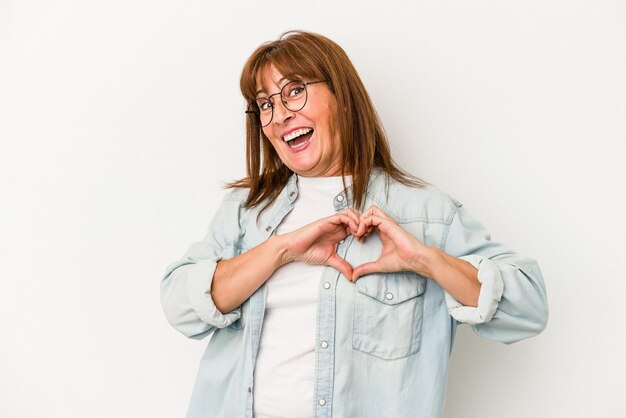 Middle age caucasian woman isolated on white background smiling and showing a heart shape with hands.