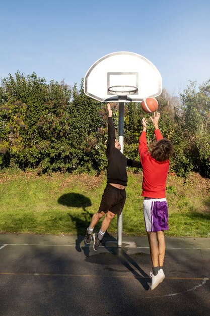 Друзья среднего возраста веселятся вместе, играя в баскетбол
