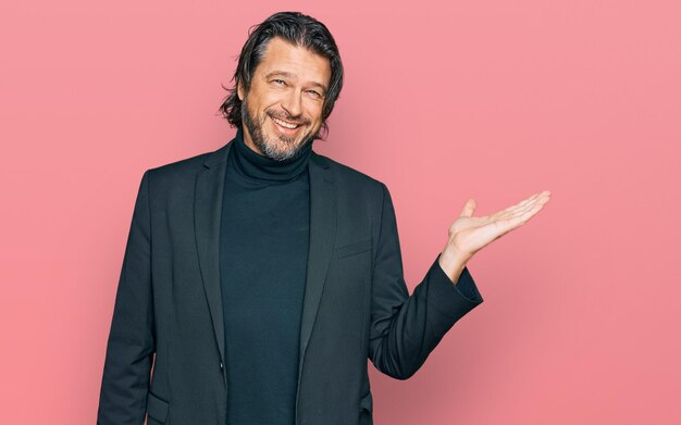 Middle age handsome man wearing business clothes smiling cheerful presenting and pointing with palm of hand looking at the camera