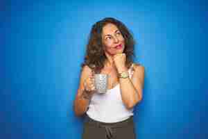 Free photo middle age senior woman drinking a cup of coffee over blue isolated background serious face thinking about question very confused idea