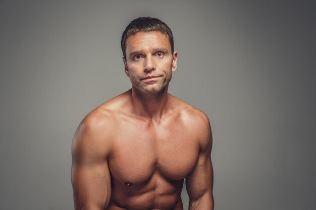 Middle age shirtless muscular man isolated on a grey background.