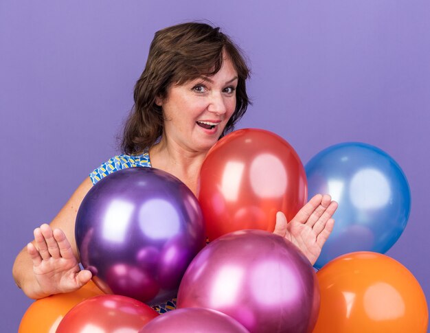 Middle age woman bunch of colorful balloons  happy and surprised
